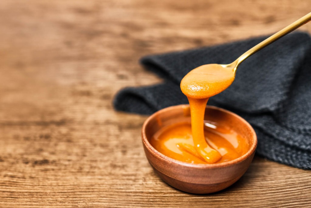 Manuka Honey with UMF or MGO being drizzled from a spoon
