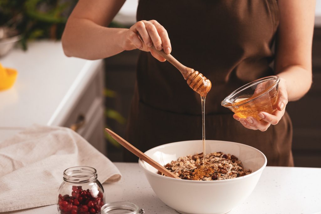 someone drizzles honey on their museli for breakfast