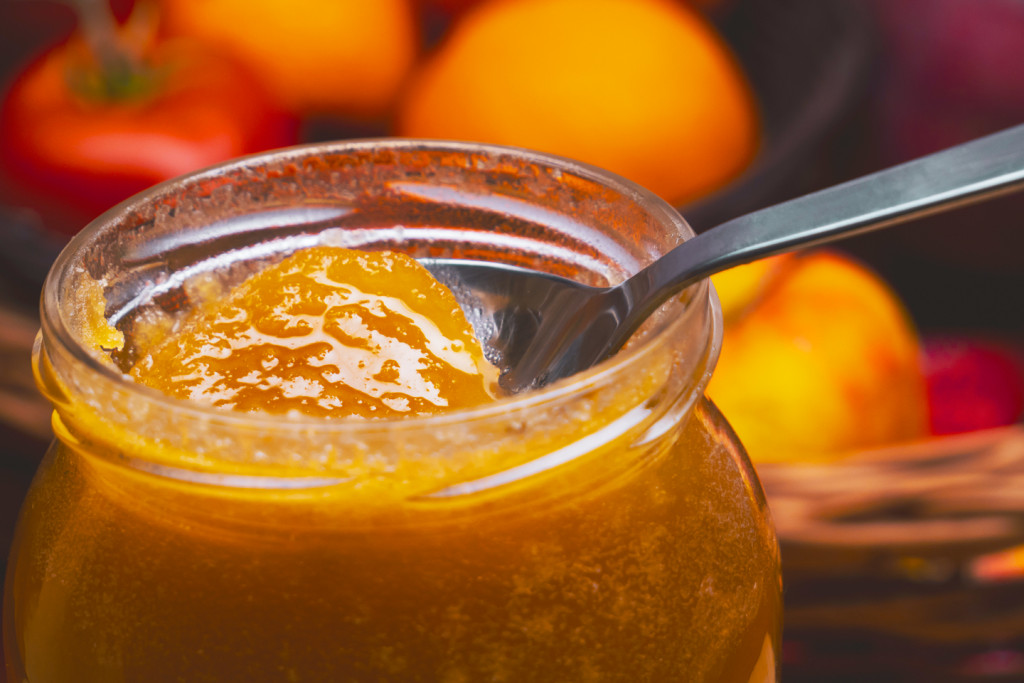 manuka honey being scooped out from a glass jar